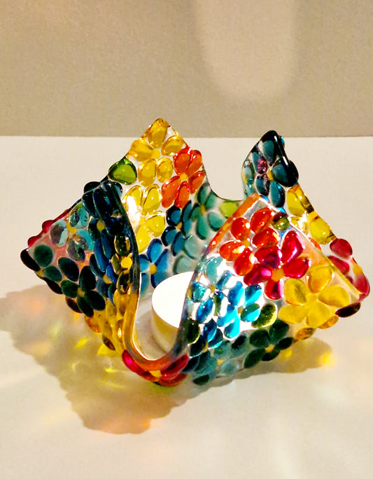 Fused glass tealight holder in a multi-coloured ditsy flower design. Side view with candle